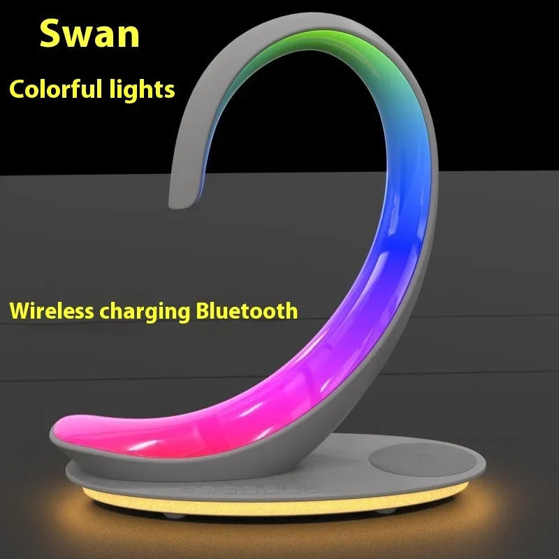 White swan sculpture desk lamp with integrated wireless phone charger and Bluetooth speaker emitting colourful light.