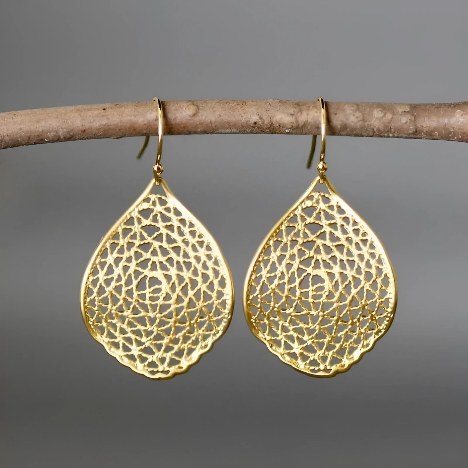 Gold-coloured retro drop earrings with a hollow leaf pendant and intricate cut-out patterns.