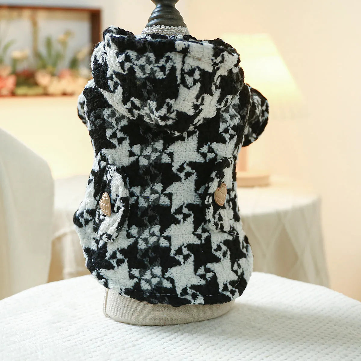 Red plaid trench coat for a dog, shown alongside a black houndstooth version, on a mannequin.