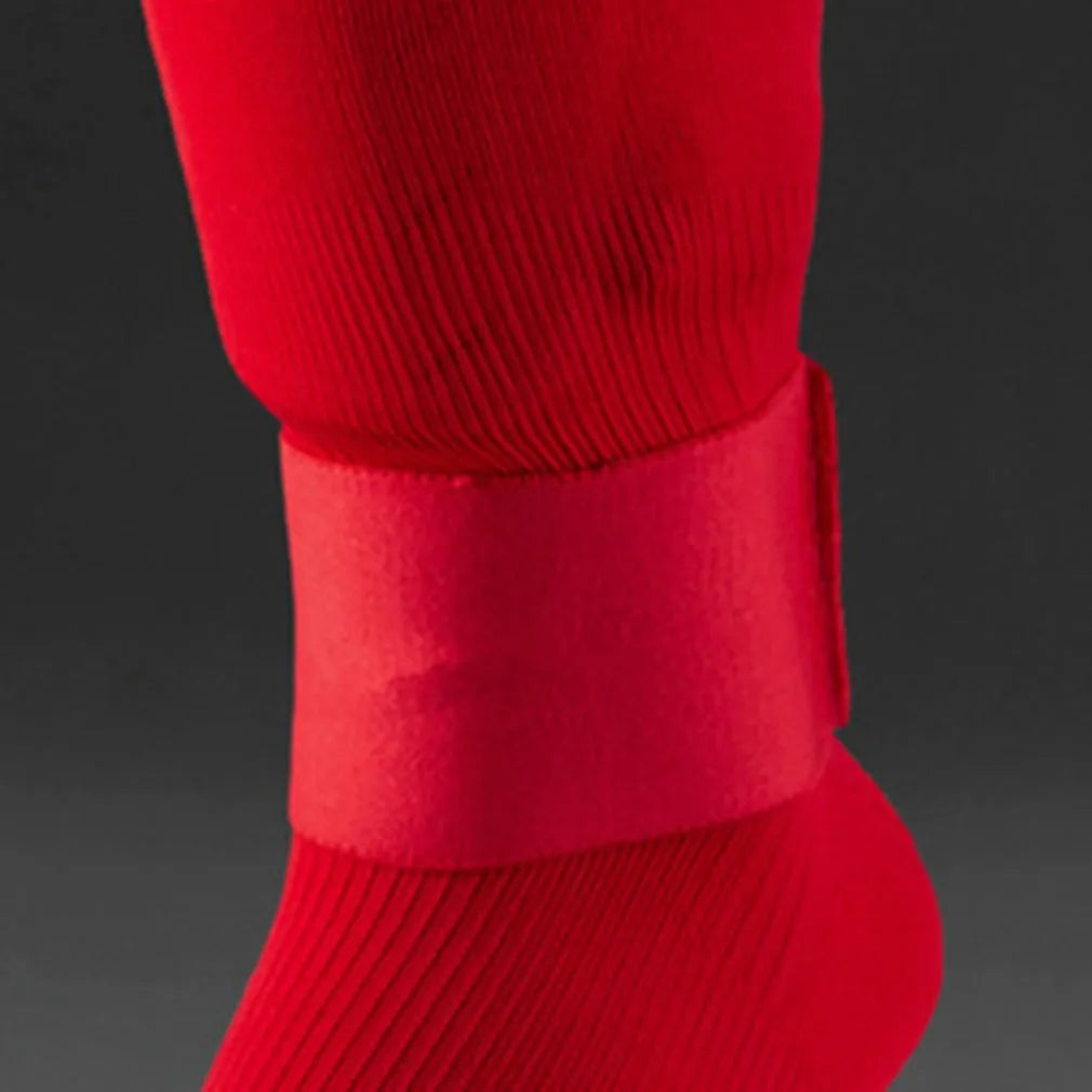 Rubber shin guard tape belt in red, shown securing a football shin pad, dimensions 25cm by 6.5cm.