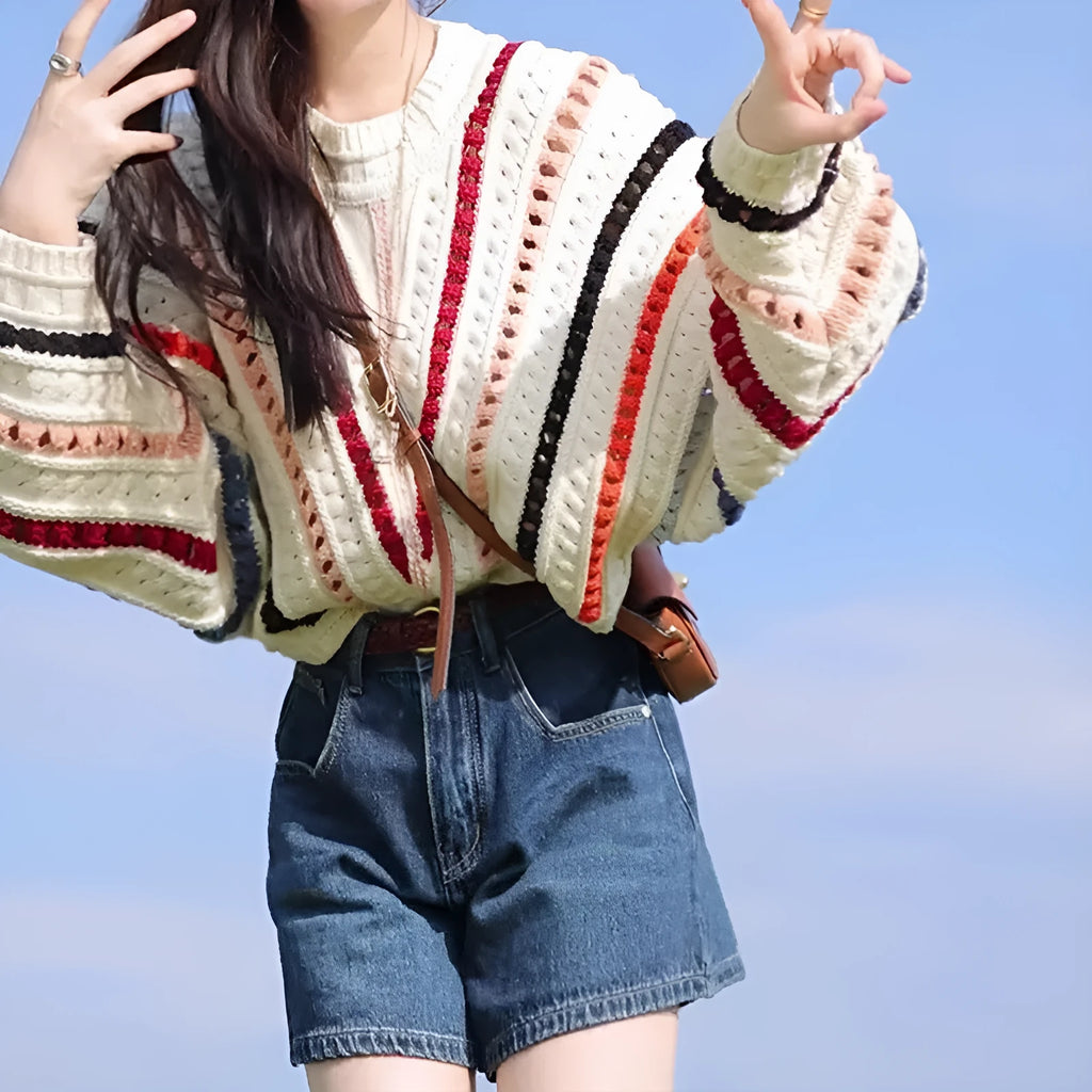 Colourful rainbow striped loose fit pullover sweater with batwing sleeves on a neutral background.