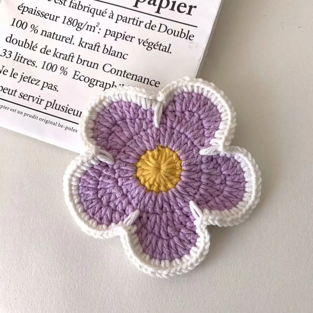 Five handmade woven flower placemats in blue, green, orange, pink and purple colours on a dining table