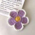 Five handmade woven flower placemats in blue, green, orange, pink and purple colours on a dining table