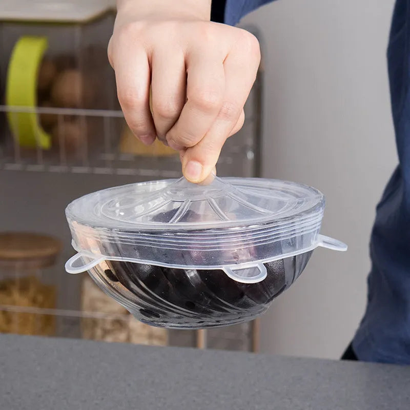 Set of six colourful silicone stretch lids in different sizes arranged on a kitchen counter.