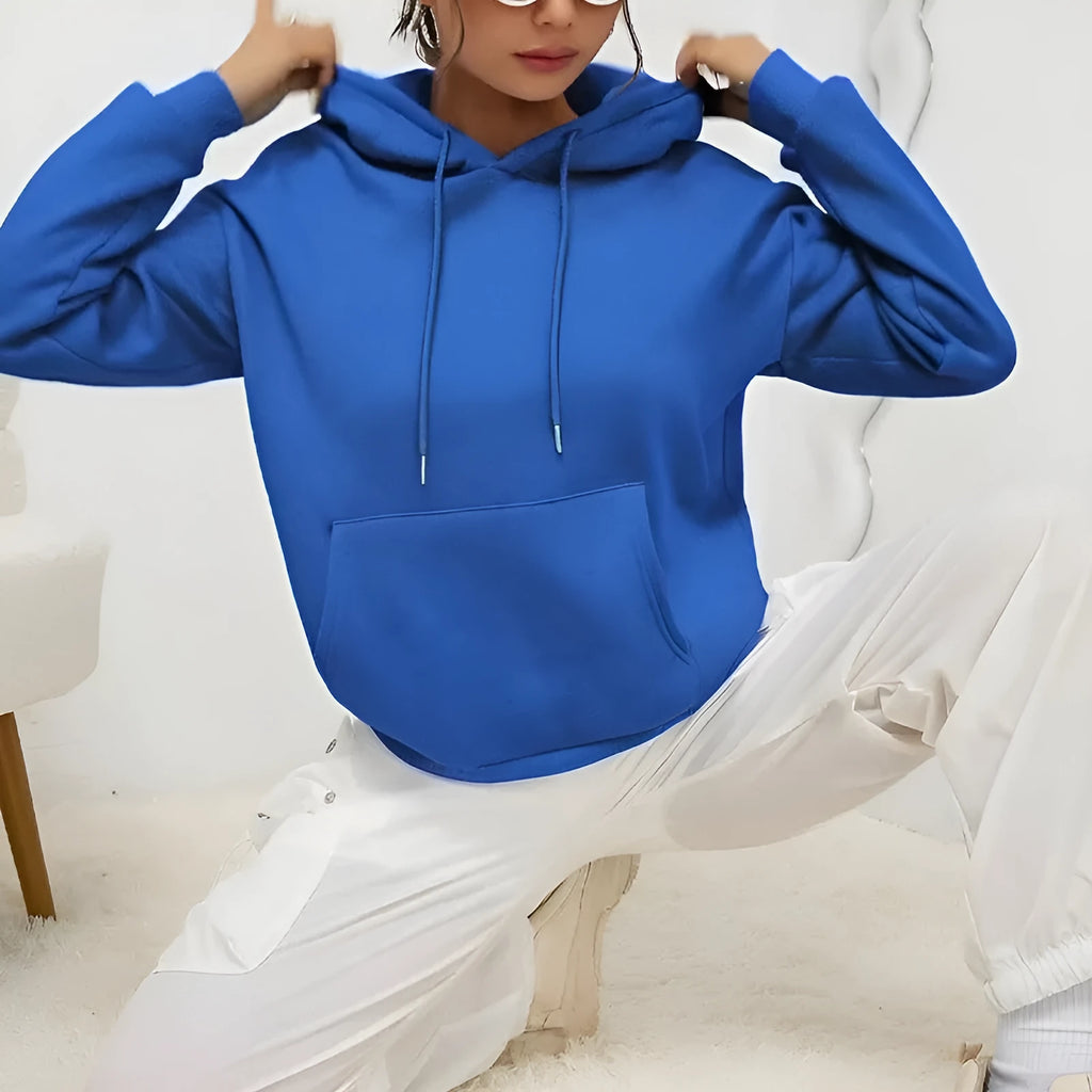 Women's loose grey drawstring hoodie with front pocket, shown in a casual setting.