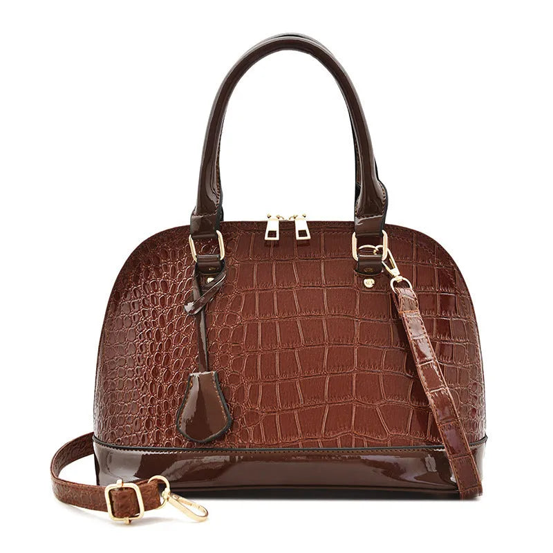 Shiny black shell-shaped crossbody bag showing front view and shoulder strap.