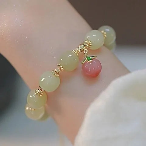 Handmade bracelet with glass beads, a rabbit charm, and a silver-coloured peace buckle on a white background.