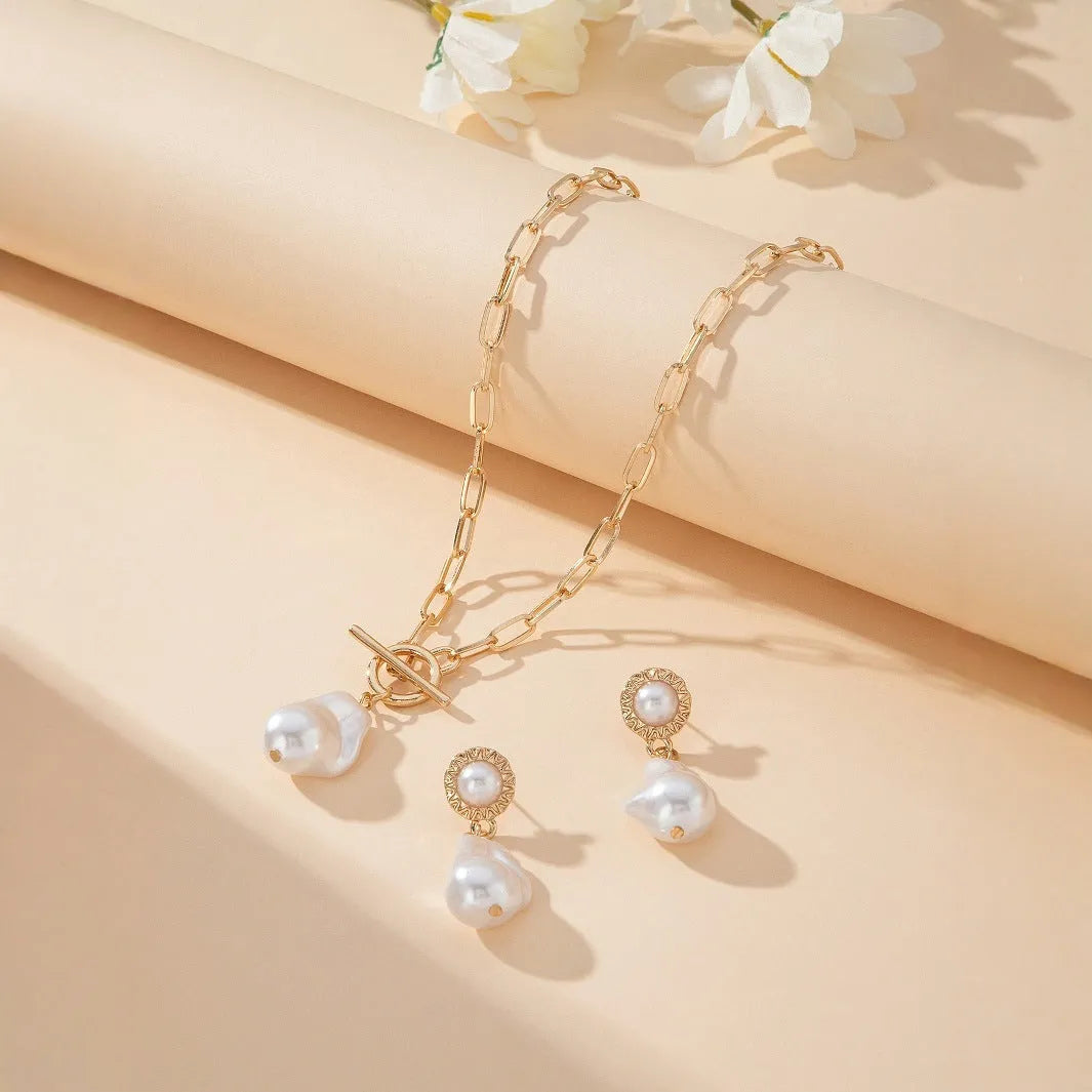 Gold tone baroque pearl pendant necklace and matching ear stud set on white background