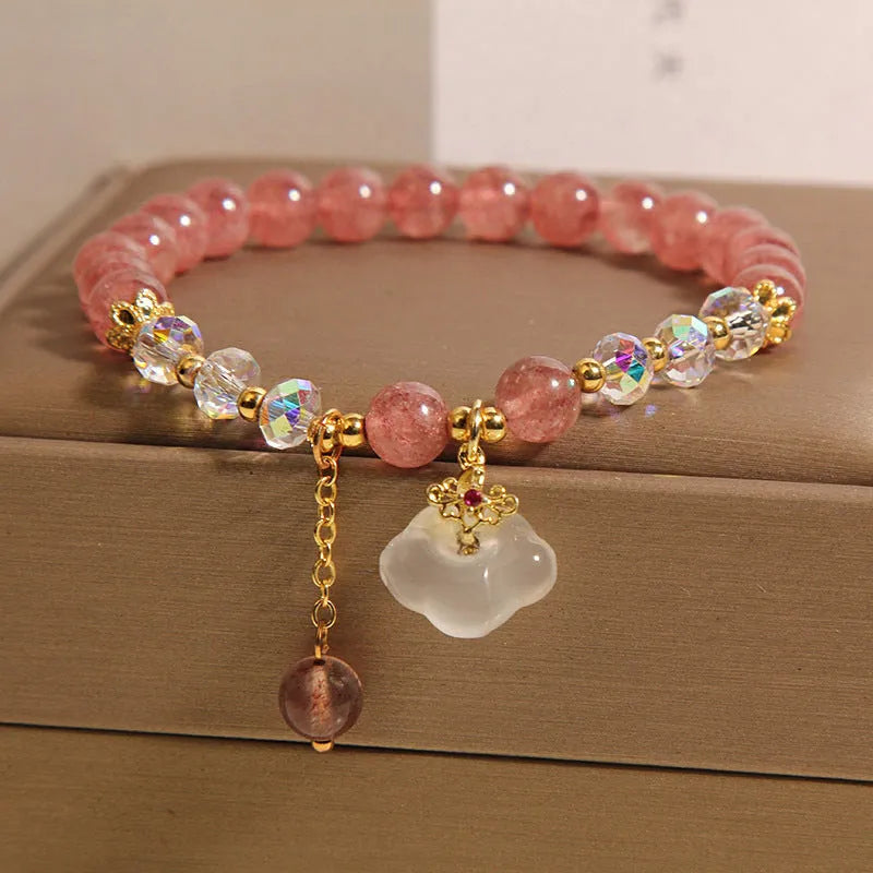 Women's bracelet with strawberry quartz and white agate beads and metal auspicious cloud charms on a white background.