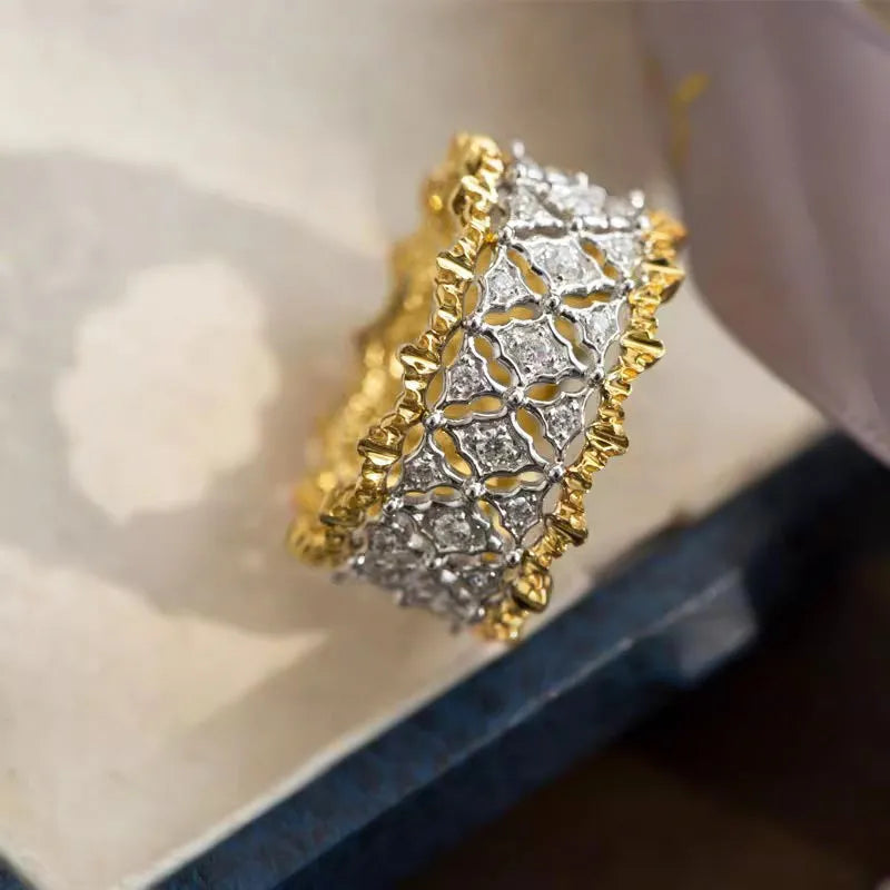 Geometric two-tone gold and silver zircon ring on a copper base, showing round stone detail.