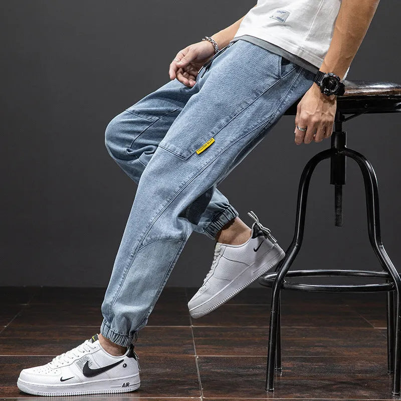 Men's loose fit straight leg cargo jeans in blue on a neutral background.