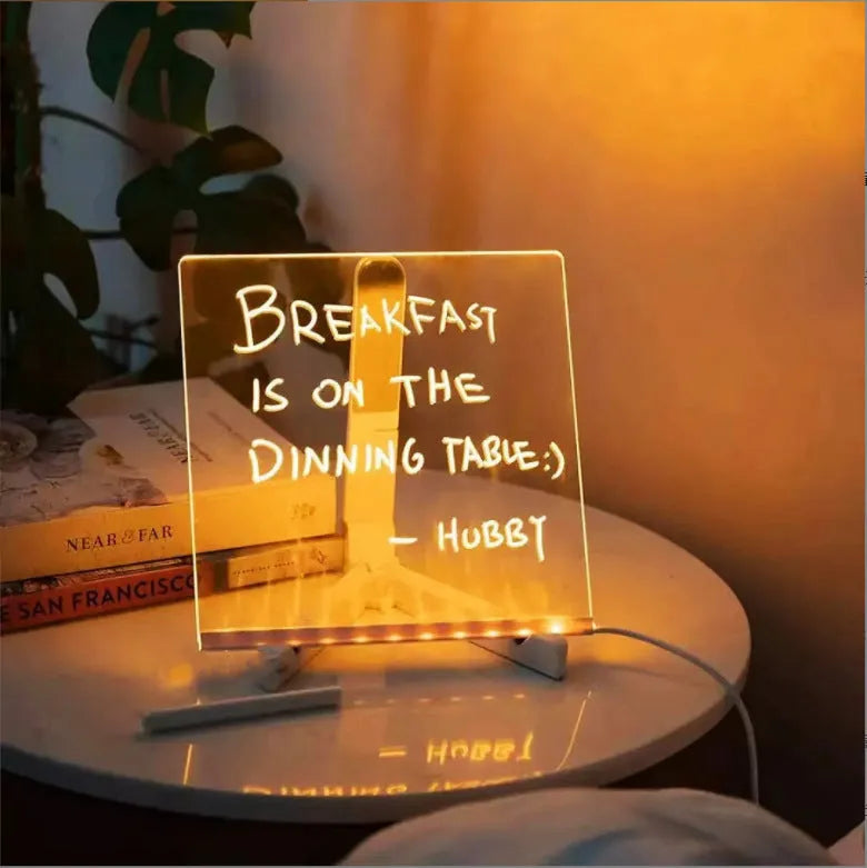 Acrylic DIY LED message board night light on a desk, showing writing on the glowing transparent surface with pens nearby.