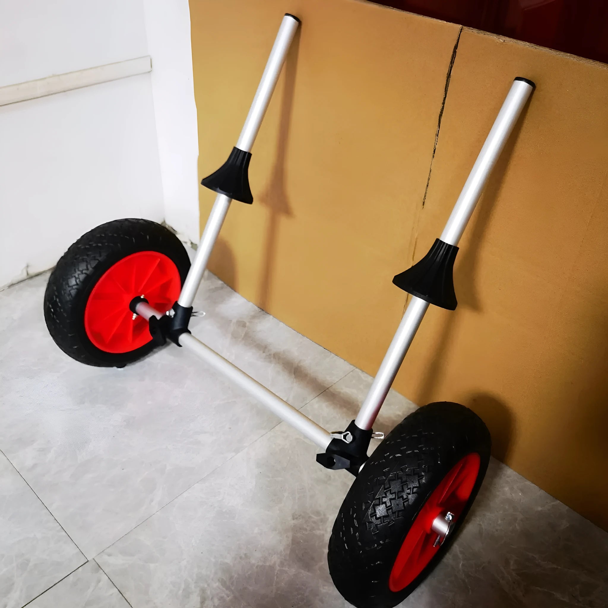 Foldable kayak beach trailer with aluminium frame and rubber wheels on sand.