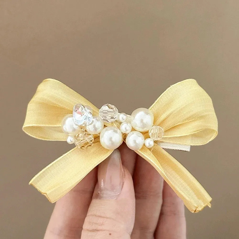 Yellow cloth bow barrette hair clip with rhinestone and pearl details on duckbill clip