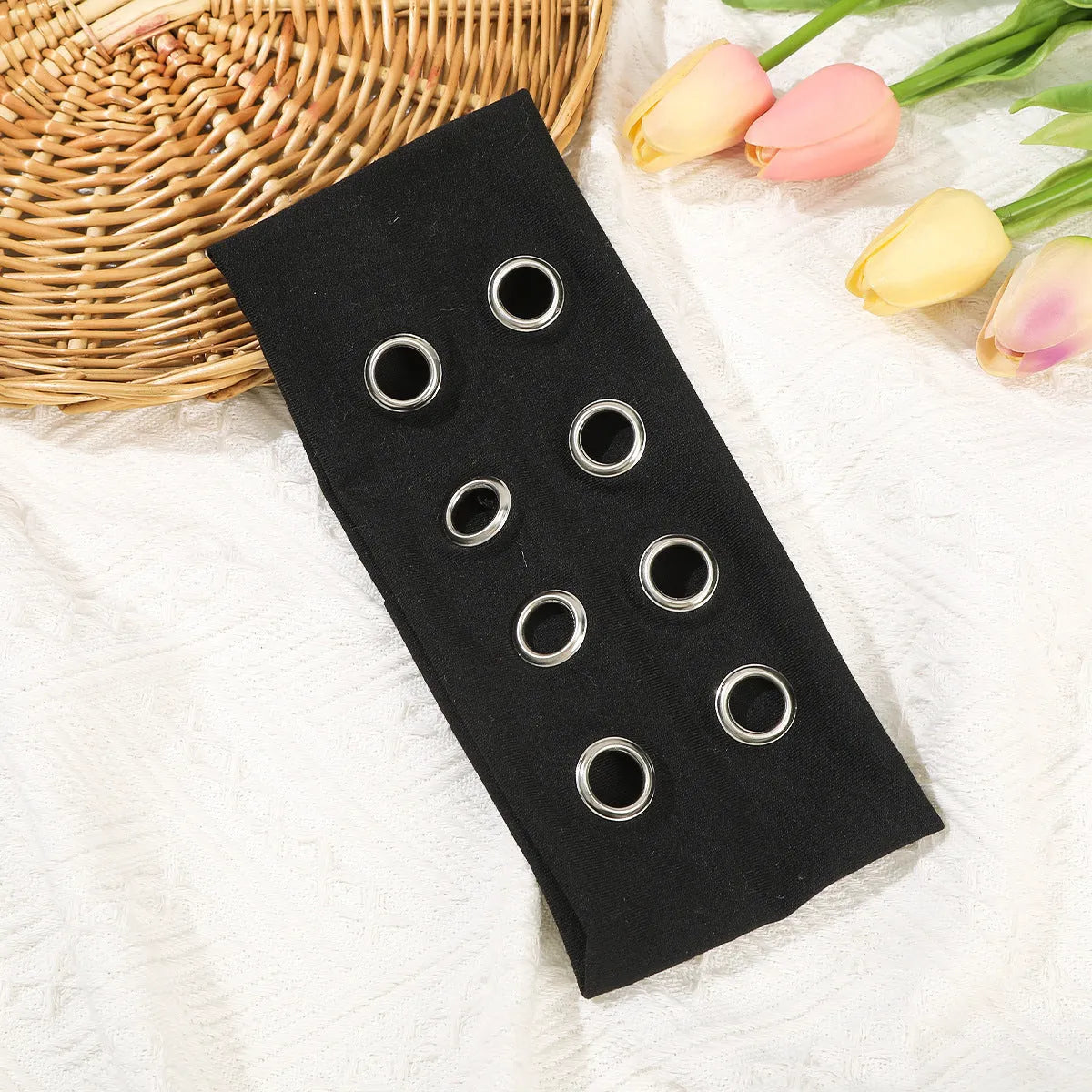 A black polyester exercise hair band with a hollow metal decorative centrepiece.
