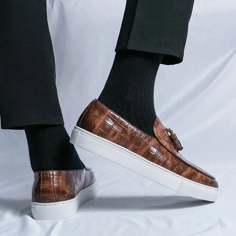 Men's black slip-on sneakers with a tassel detail on the round-toe upper.