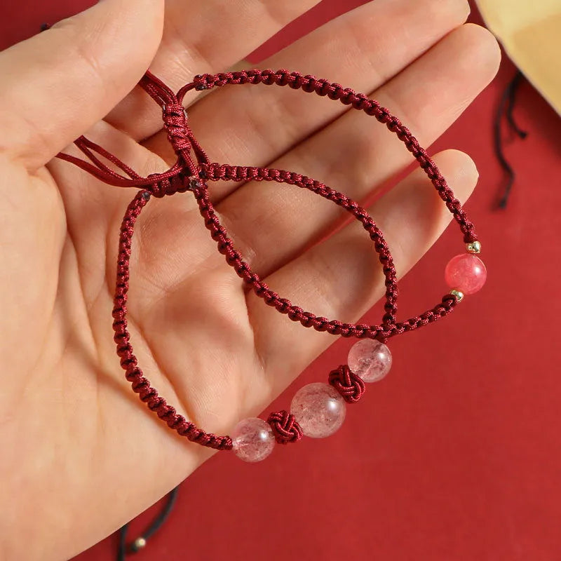 Woven red rope bracelet with spherical strawberry quartz or obsidian beads and an alloy clasp.