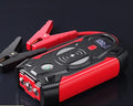 Red car emergency jump starter power pack with connection clips on a black background