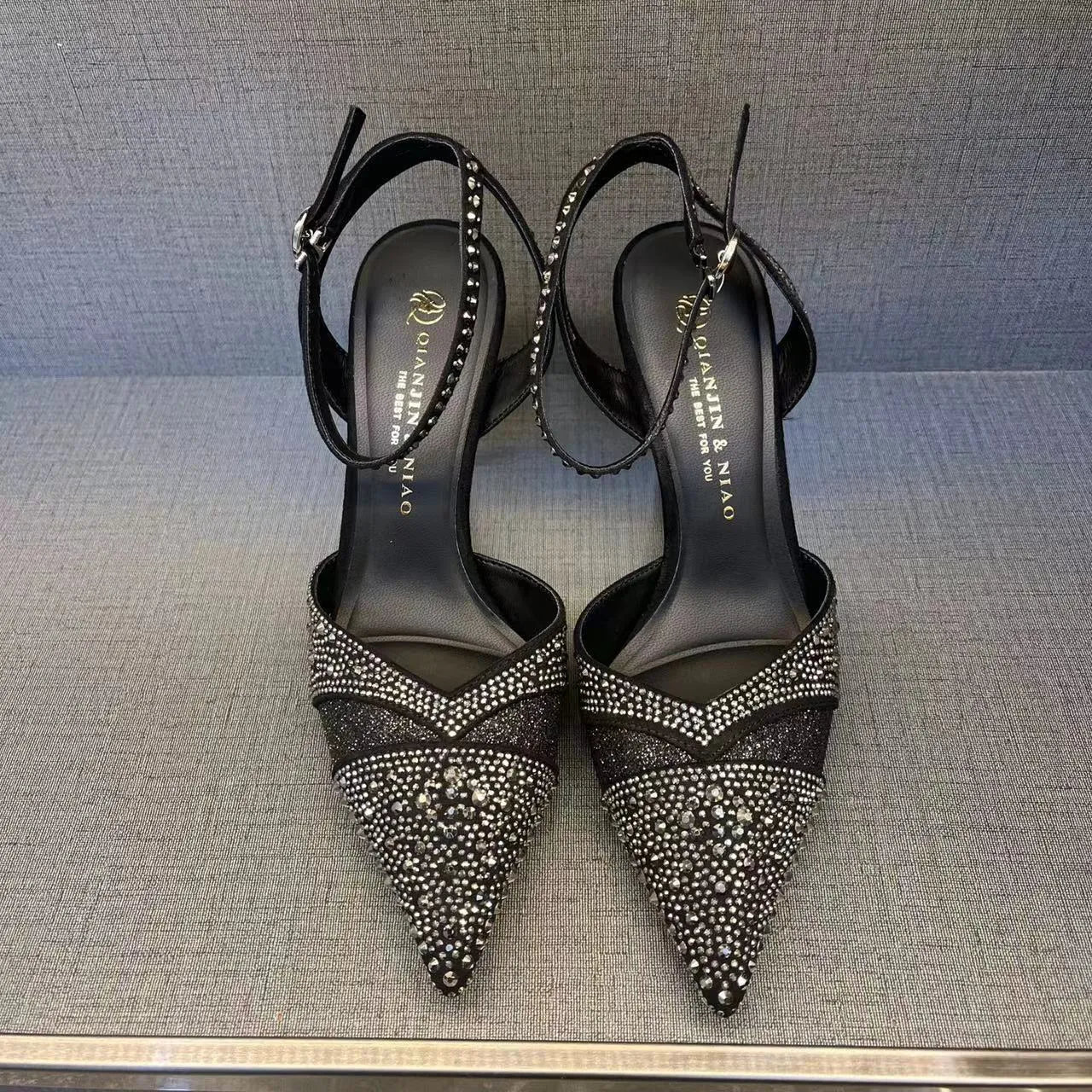 Women's black hollow high heel court shoe with red sole and pointed toe, stiletto heel.