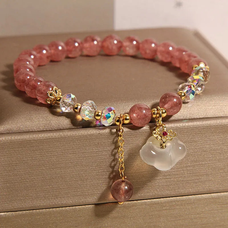 Women's bracelet with strawberry quartz and white agate beads and metal auspicious cloud charms on a white background.