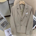 Women's black short suit coat with loose fit and pocket detail on hanger