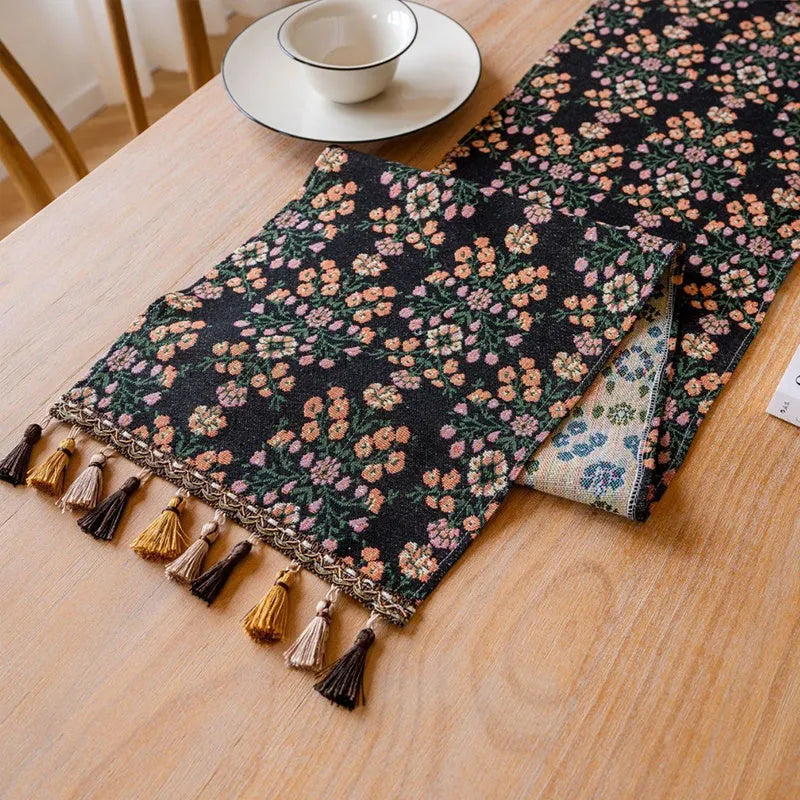 Nordic jacquard bouquet pattern table runner with tassel trim in dark blue on a dining table.