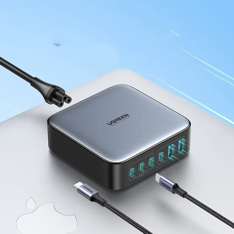 White 100W GaN charging plug with four USB-C ports next to its included 1.5m charging cable on a desk.