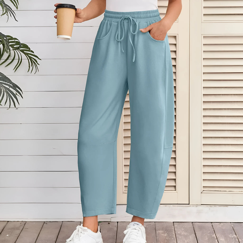 Woman wearing loose light grey cropped sweatpants with drawstring waist and side pockets