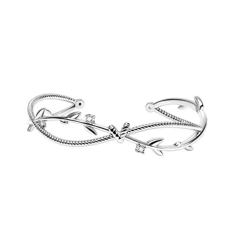 White gold sprout branch bracelet with cross twisted design on a wrist.