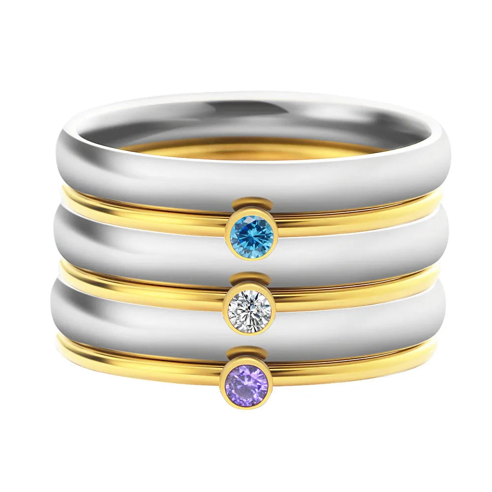 Close-up of a titanium steel ring with an engraved geometric design and a December colour birthstone.