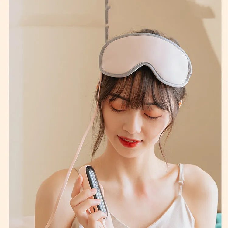 Pink portable eye SPA mask with suede shell on a grey background, showing USB port.