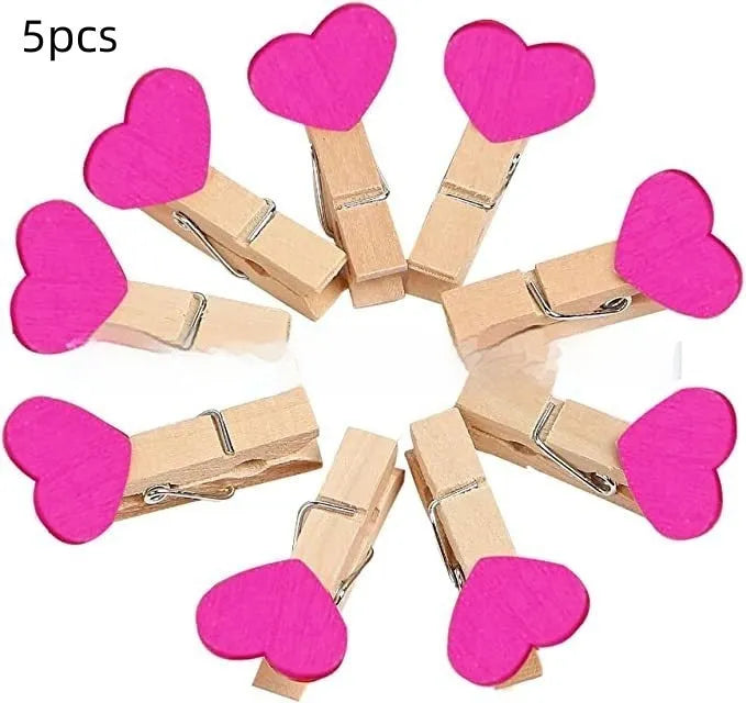Five handmade wooden heart-shaped clips in red, white, and rose red on a surface.