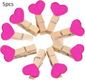 Five handmade wooden heart-shaped clips in red, white, and rose red on a surface.