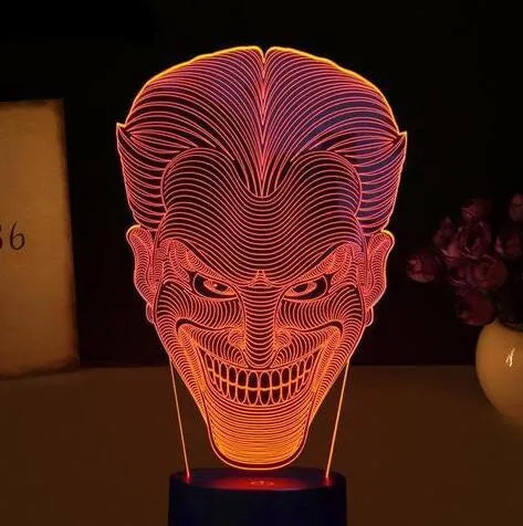 A 3D acrylic LED lamp with a square base, displaying one of its seven colour options on a desk.
