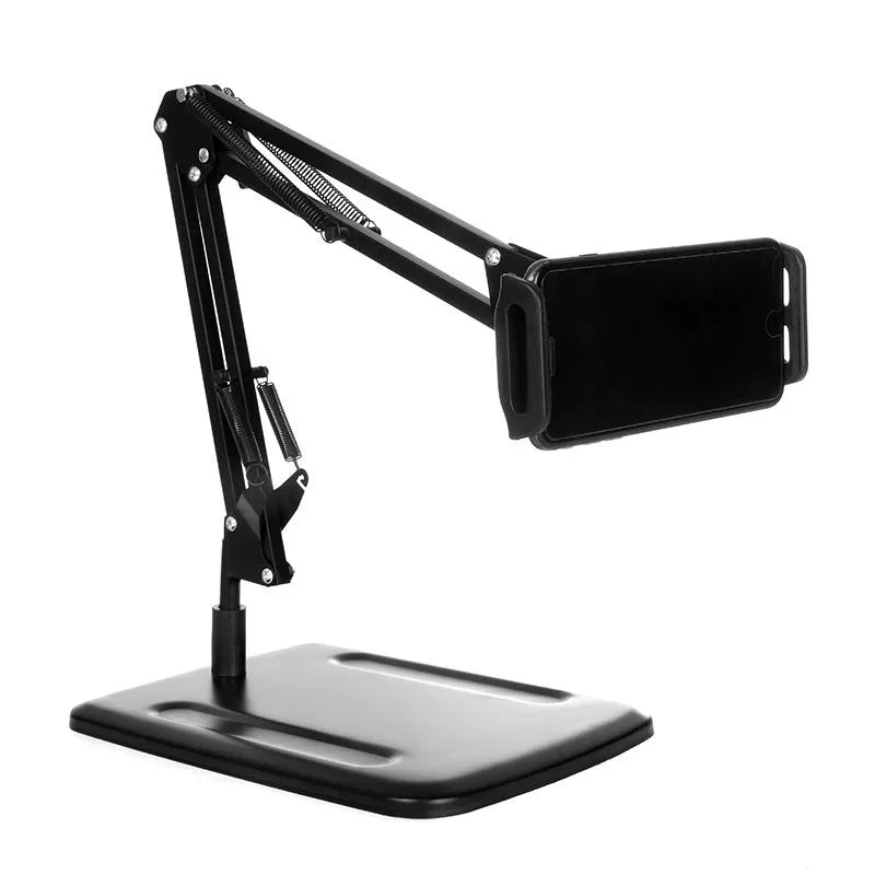 Black universal phone stand with long rotating metal arms and a heavy round base on a wooden desk.