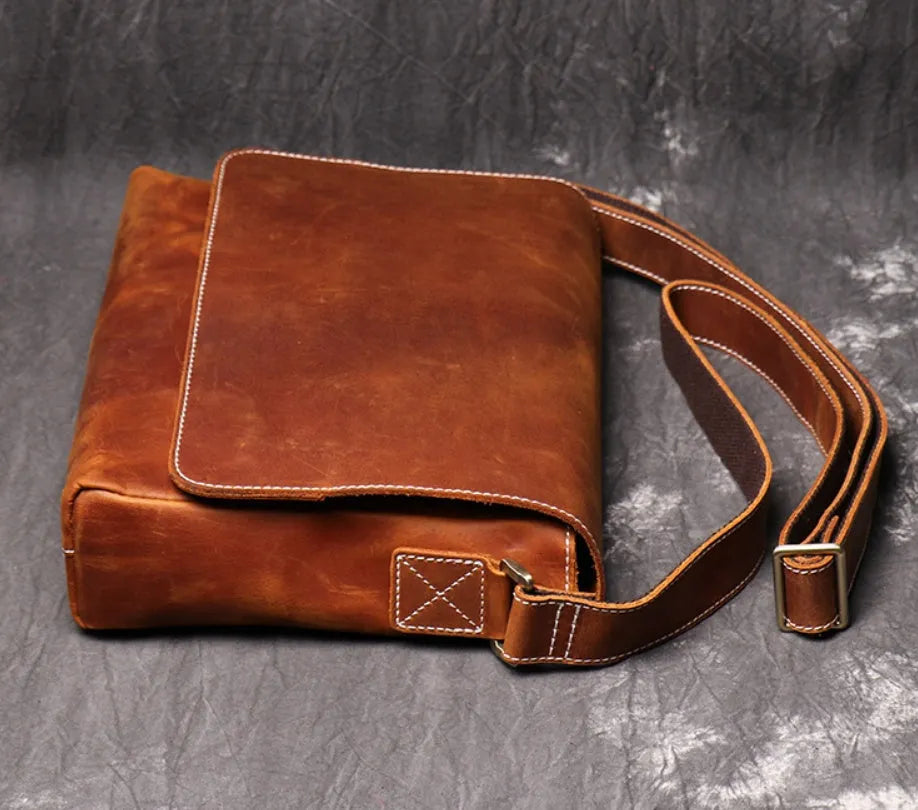 Vintage brown leather men's messenger bag with flap opening and adjustable shoulder strap.