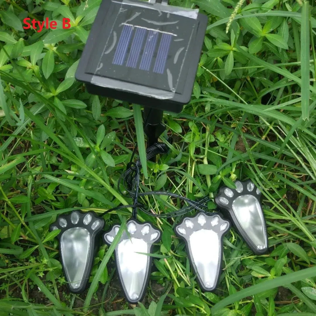 Four black solar-powered bear paw print garden lights with solar panel pole