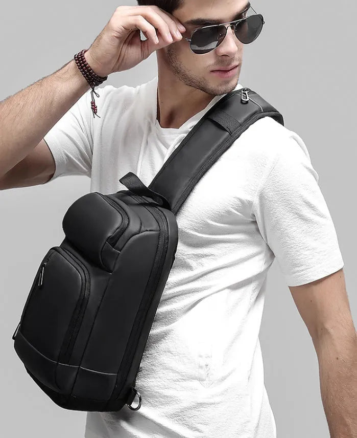Black medium-sized PVC outdoor shoulder bag with an air cushion strap and internal organiser pockets.