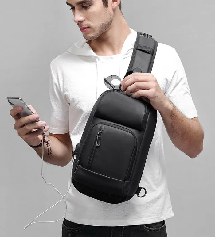 Black medium-sized PVC outdoor shoulder bag with an air cushion strap and internal organiser pockets.