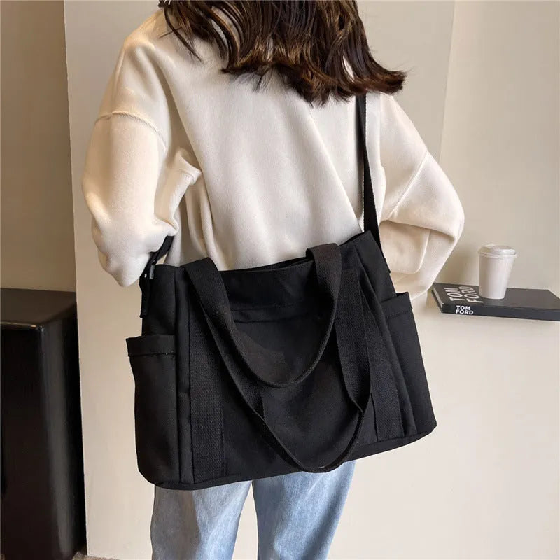 Polyester shoulder tote bag in solid colour with external sandwich pocket and internal phone pouch.