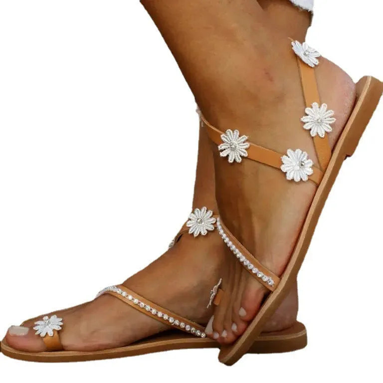 Brown women's Roman sandals with floral pattern and flat rubber sole.