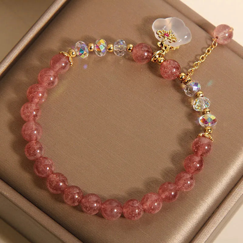 Women's bracelet with strawberry quartz and white agate beads and metal auspicious cloud charms on a white background.
