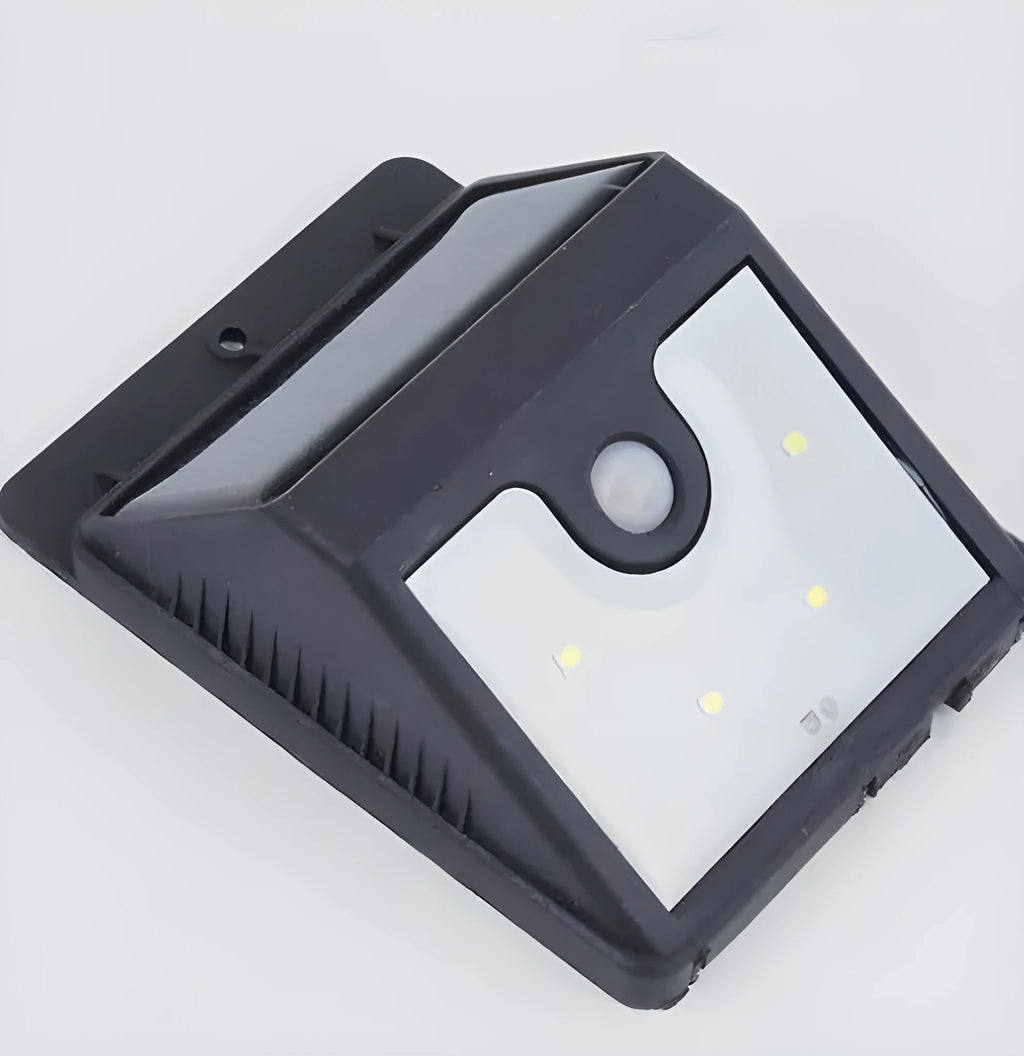 Grey solar-powered outdoor security light with four LED panels and a motion sensor mounted on a wall.