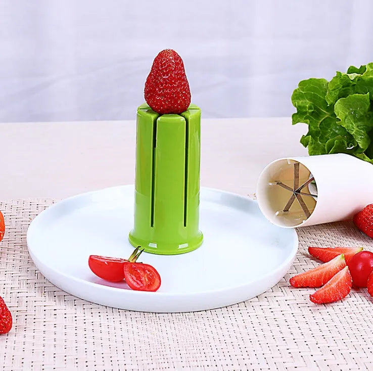 White kitchen slicer with six stainless steel blades for cutting cucumbers, carrots, and strawberries.