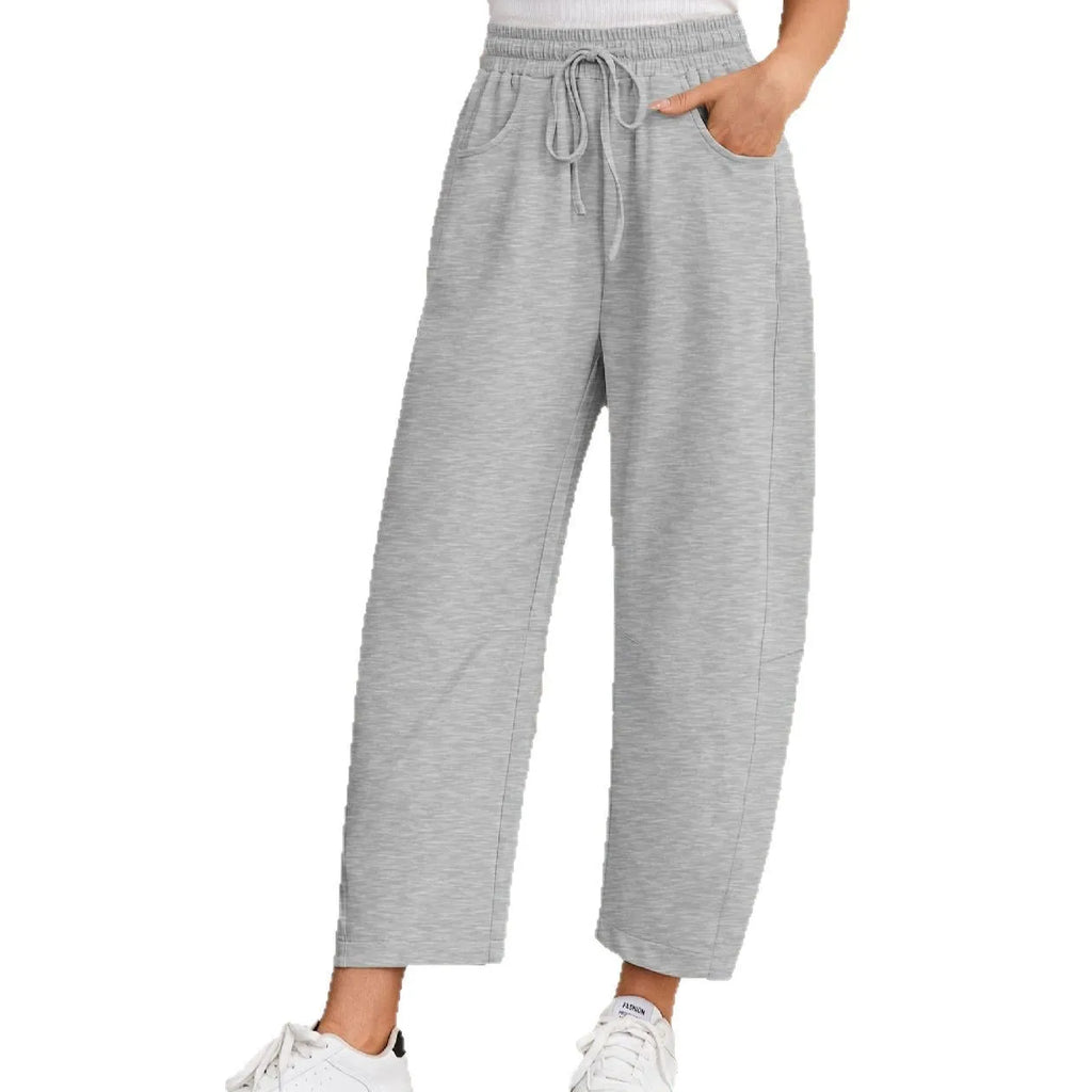 Woman wearing loose light grey cropped sweatpants with drawstring waist and side pockets