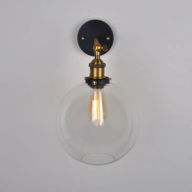 Close-up of a retro-style spherical glass wall lamp in amber, showing its aluminium holder and round shape.