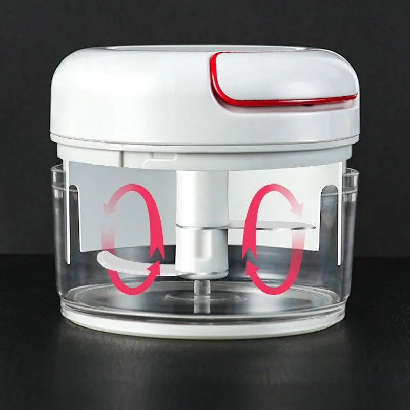 White manual food chopper with stainless steel blades on a magnet, shown with garlic and vegetables.