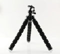 Black flexible octopus tripod wrapped around pole holding smartphone for video recording