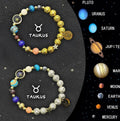 Two natural stone beaded bracelets showing different zodiac sign designs on a table.