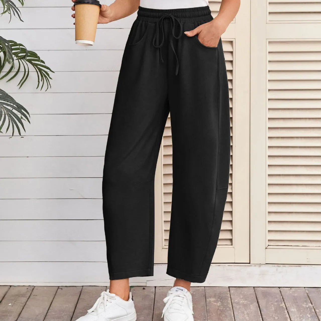Woman wearing loose light grey cropped sweatpants with drawstring waist and side pockets